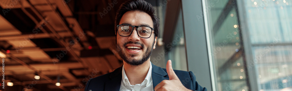 Indian businessman is making notes in notepad during working day in cafe and showing thumb up Indian businessman is making notes in notepad during working day in cafe and showing thumb up