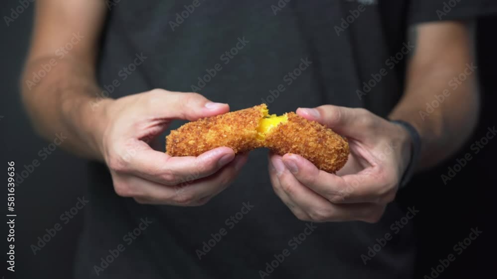 Male food blogger pulls a crispy mozzarella croquette apart, medium shot Male food blogger pulls a crispy mozzarella croquette apart, medium shot