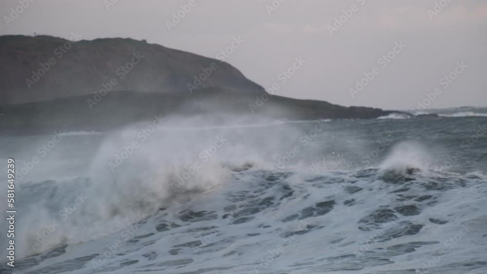 Huge waves with spray and foam rolling over coastal area at sunset blue hour. Handheld camera Huge waves with spray and foam rolling over coastal area at sunset blue hour. Handheld camera
