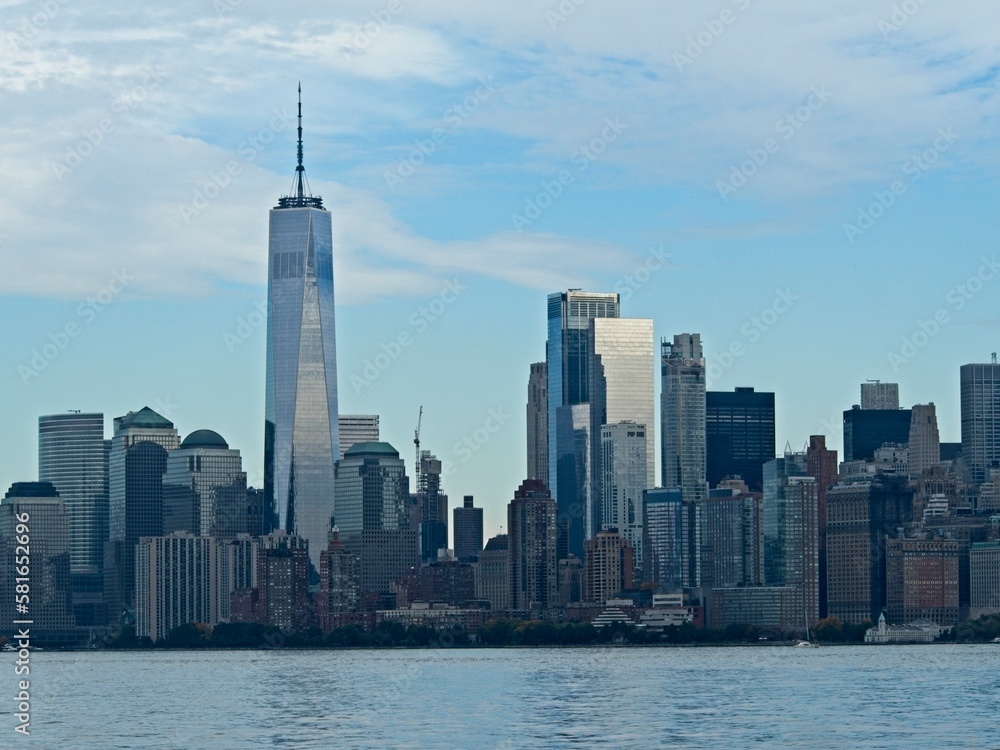 Obraz premium Looking back on Manhattan from the Hudson River and Liberty Island, as the towering high rises of Lower Manhattan loom above the river