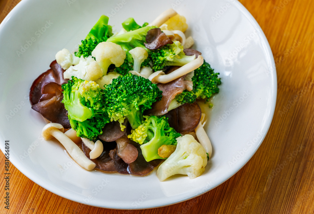 Healthy food menu, stir-fried mushrooms, cauliflower, and broccoli, Thai healthy mix vegetable food on a white plate. Close-up image, view from above. Healthy food menu, stir-fried mushrooms, cauliflower, and broccoli, Thai healthy mix vegetable food on a white plate. Close-up image, view from above.