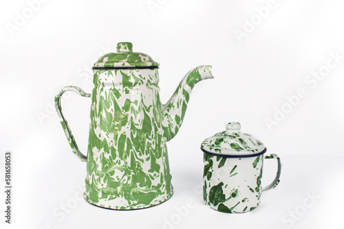 A vintage green white teapot and a small green cup are next to it. isolated on white background