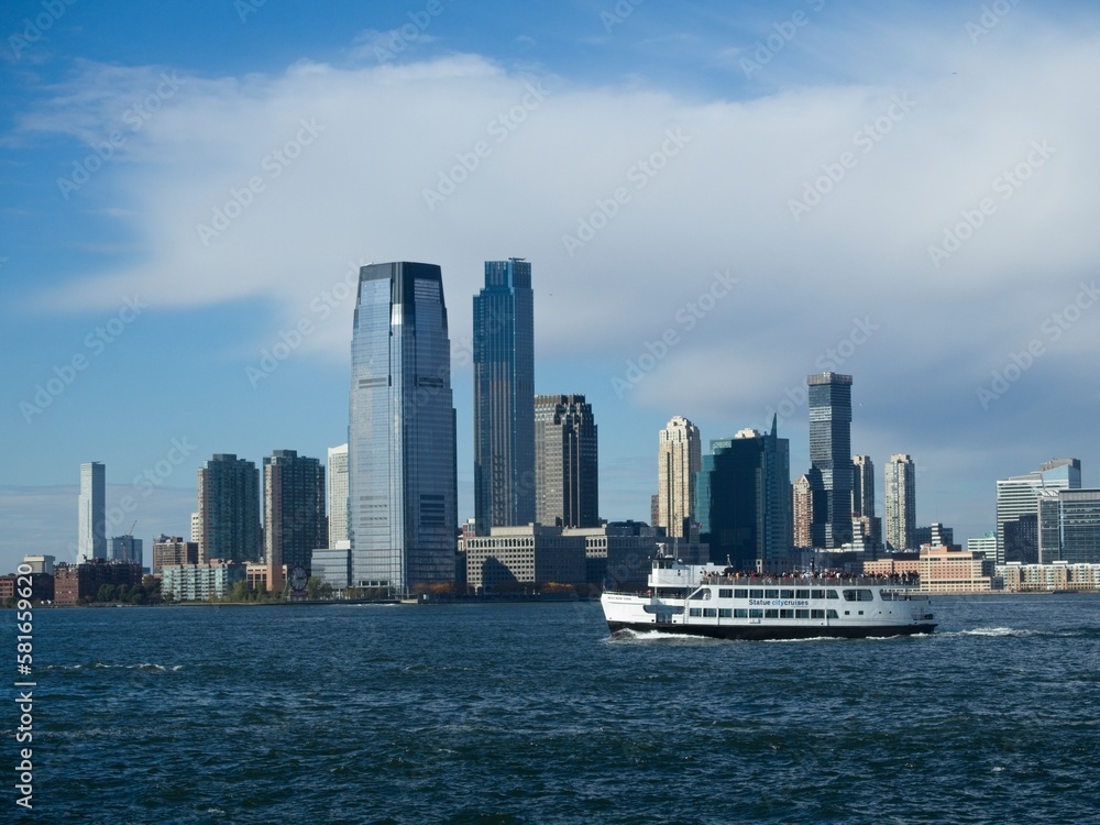 Looking back on Manhattan from the Hudson River and Liberty Island, as the towering high rises of Lower Manhattan loom above the river Looking back on Manhattan from the Hudson River and Liberty Island, as the towering high rises of Lower Manhattan loom above the river