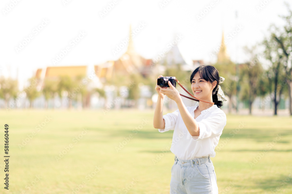 Portrait of asian woman traveler using camera. Asia summer tourism vacation concept with the grand palace in a background at Bangkok, Thailand Portrait of asian woman traveler using camera. Asia summer tourism vacation concept with the grand palace in a background at Bangkok, Thailand