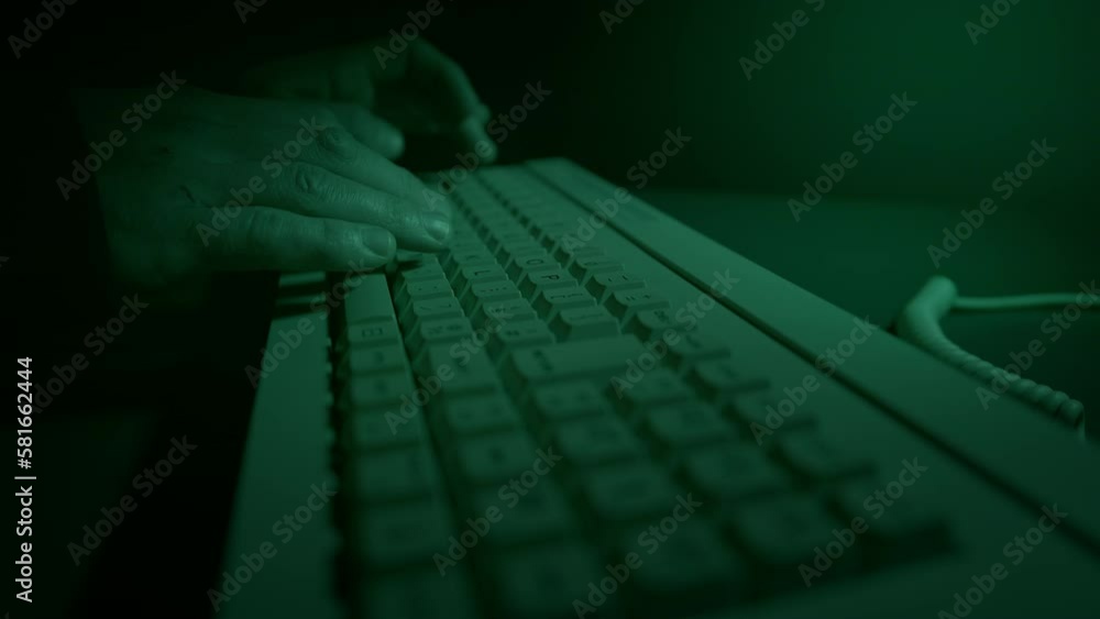 A hacker types on a vintage 1980s computer keyboard in a dark room. The ...