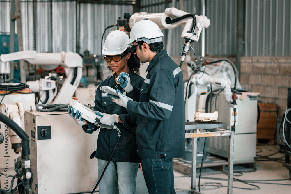 The robotic welding supervisor advice female worker to use a remote control panel display to automate the welding operation with higher accuracy. The learning way to apply basic principles of welding The robotic welding supervisor advice female worker to use a remote control panel display to automate the welding operation with higher accuracy. The learning way to apply basic principles of welding