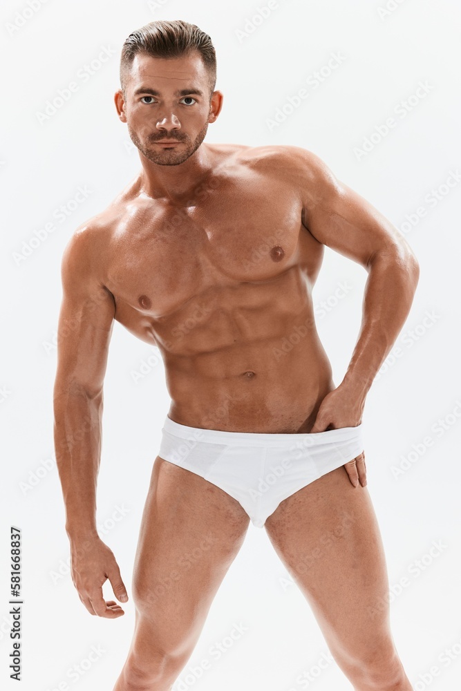 Man athletic body bodybuilder in briefs with naked torso abs full-length in the background, fitness classes. Advertising, sports, active lifestyle, competition, challenge concept. Man athletic body bodybuilder in briefs with naked torso abs full-length in the background, fitness classes. Advertising, sports, active lifestyle, competition, challenge concept.
