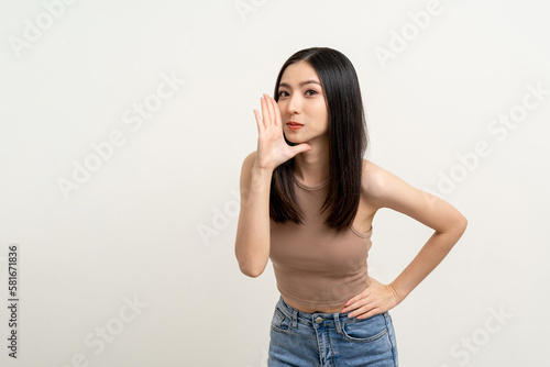 Happy beautiful asian woman with copy space. Excited pretty girl shout out loud wow with hands on mouth announcement standing pose on isolated white background. © Chanakon