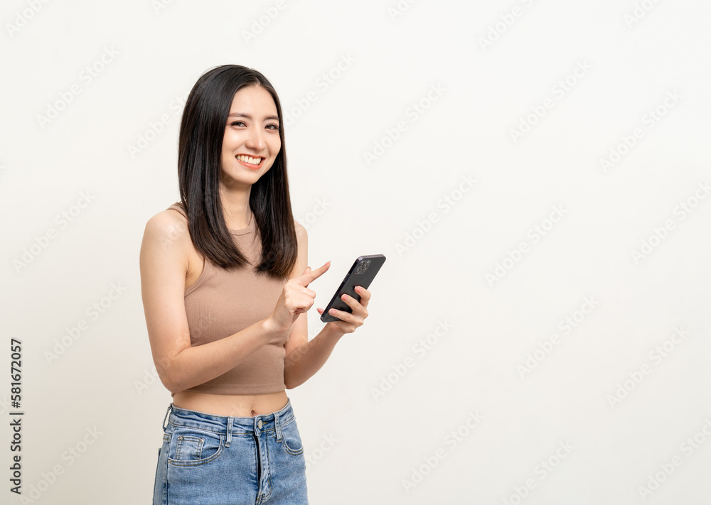 Pretty young asian woman using smartphone standing on isolated white background. Excited Beautiful young asian shopping online payment with mobile phone. Playing game on smartphone Pretty young asian woman using smartphone standing on isolated white background. Excited Beautiful young asian shopping online payment with mobile phone. Playing game on smartphone