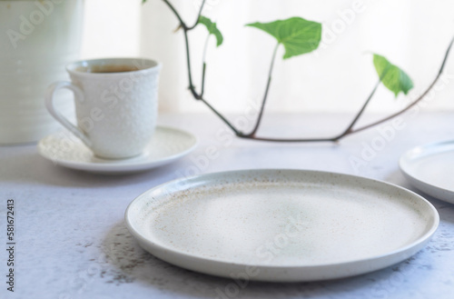 empty ceramic plate with a glass of coffee and plant in the background