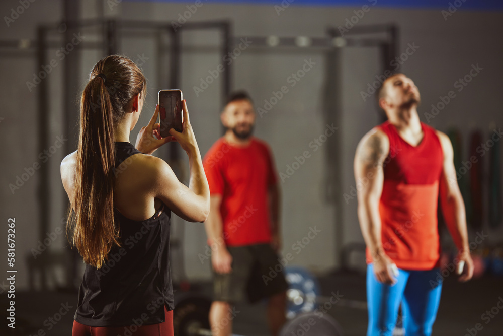 Woman taking picture with smartphone in gym. Woman taking picture with smartphone in gym.