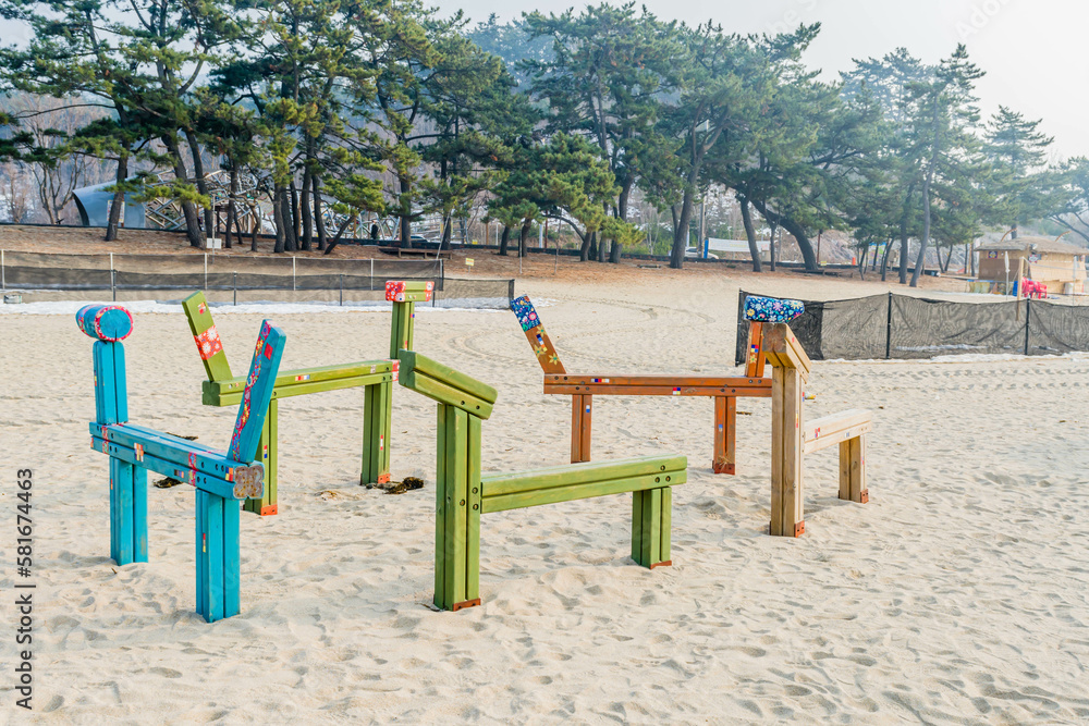 Wooden benches shaped like a horse on empty beach.