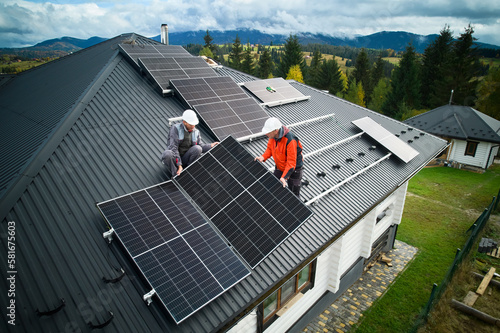 Foto Engineers building photovoltaic solar module station on roof of house