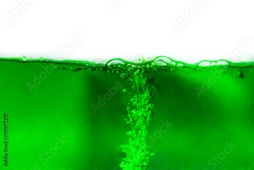 Close-up shot of green soda drink with bubbles on white background. Isolated