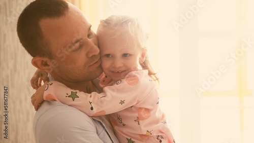 Father's Day. Close-up of a portrait of a father and his daughter, clinging to his shoulder, and crying. The father cradles and comforts his little daughter