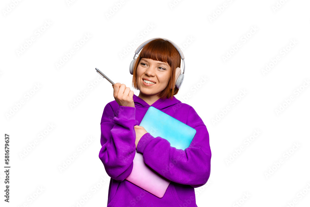 Smiling girl wearing headphones, holding a laptop and pointing to the left Smiling girl wearing headphones, holding a laptop and pointing to the left