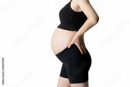 Pregnant woman sticking out her abdomen and covering it with her hands (isolated on white background)