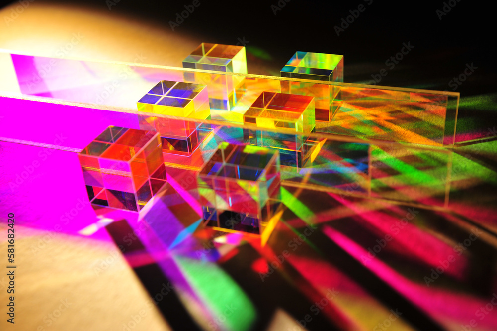 Artistic dispersion of artificial light, dichroic square glass cube and horizontal stripe scattering narrow beam of light into several colours of spectrum on texture white paper background. Artistic dispersion of artificial light, dichroic square glass cube and horizontal stripe scattering narrow beam of light into several colours of spectrum on texture white paper background.