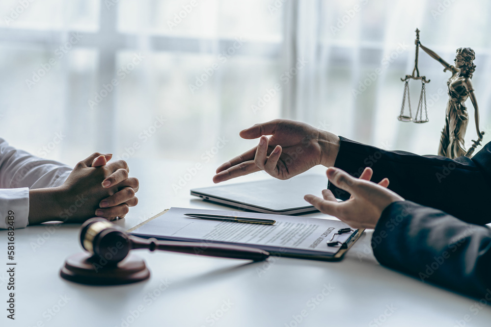Fototapeta premium Lawyer working with client discussing contract documents with brass scales on law in courtroom Consulting to help clients win court cases.