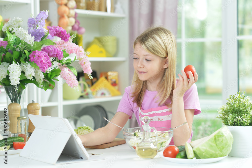 Cute little girl holding tomato and looking at tablet Cute little girl holding tomato and looking at tablet