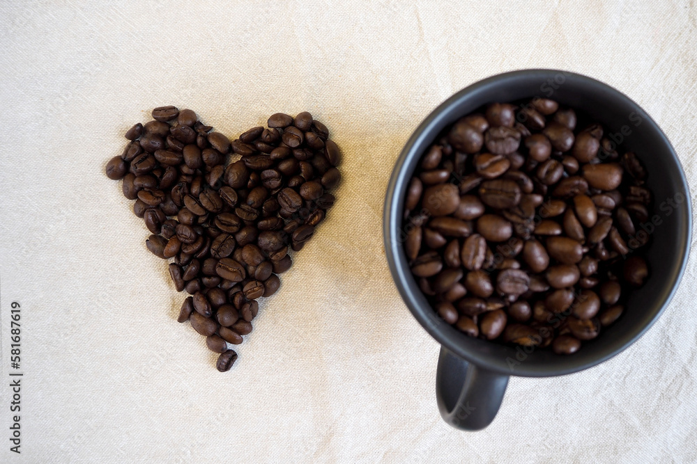 the dark mug is filled with whole grains of coffee. heart made from coffee beans. view from above . cheerfulness, energy the dark mug is filled with whole grains of coffee. heart made from coffee beans. view from above . cheerfulness, energy