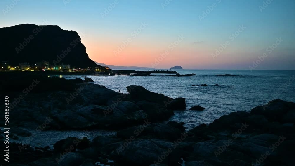 A seaside village lights up against a dreamy orange sky at dusk. The peculiar rocky landscape of Ruifang Nanya, New Taipei City. Taiwan A seaside village lights up against a dreamy orange sky at dusk. The peculiar rocky landscape of Ruifang Nanya, New Taipei City. Taiwan
