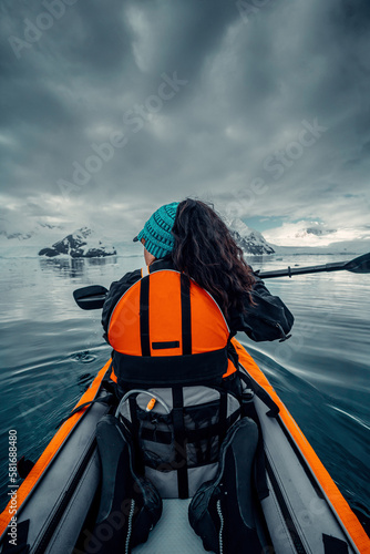 Vertical Shot of Female Kayaker Navigates Her Way Through Calm Waters of Antarctica, Woman in Orange Life Vest, Scenic Views of Arctic landscape