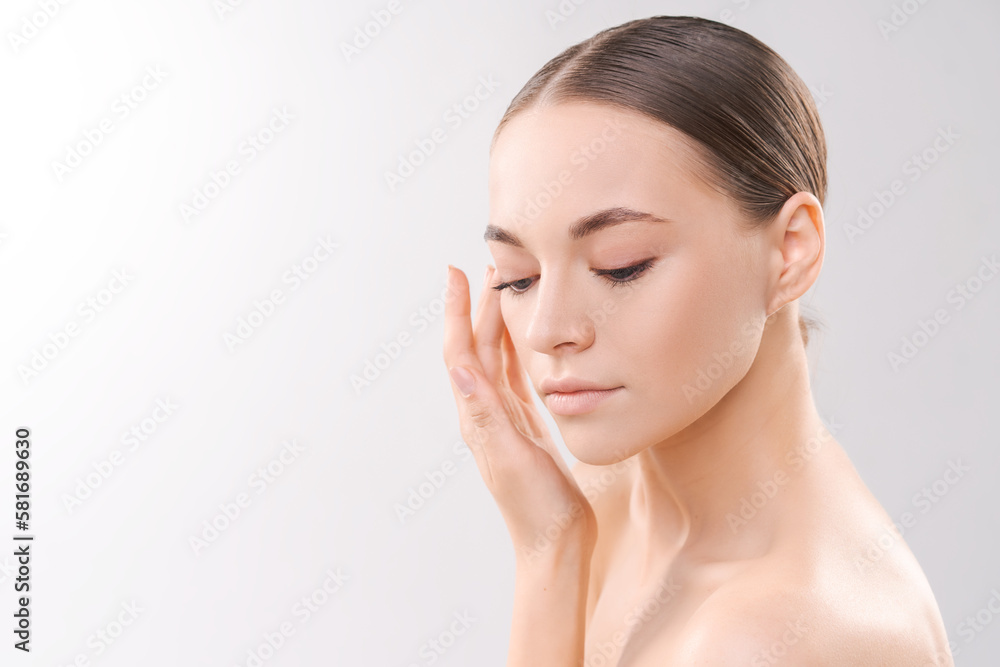 To camera isolated on background. Young woman close-up portrait. Healthy facial skin care beauty, age skin care cosmetic touches with hand, cosmetology concept To camera isolated on background. Young woman close-up portrait. Healthy facial skin care beauty, age skin care cosmetic touches with hand, cosmetology concept
