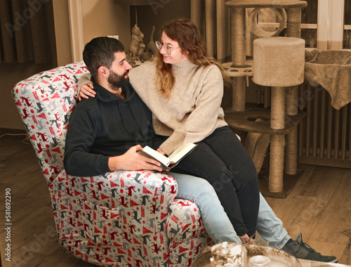 Young couple on a comfortable armchair reading a book together