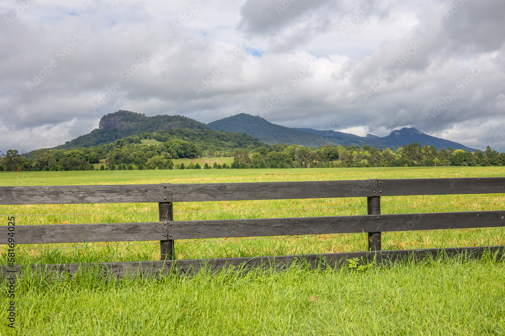 Hills touched by low cloud with meadows and a wooden fence in the foreground