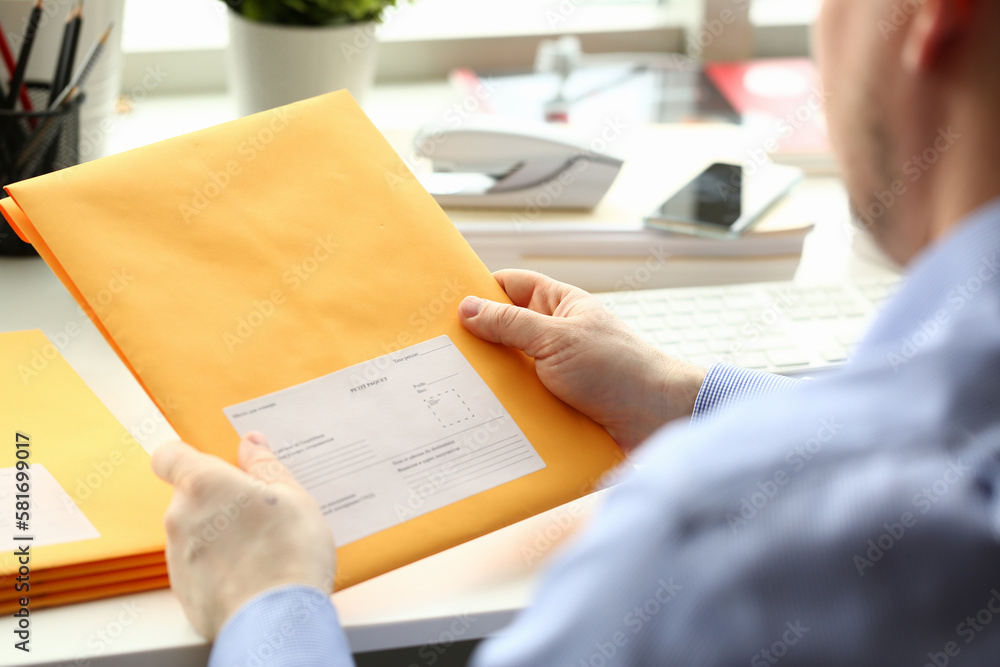 Businessman holding yellow package with mail in office