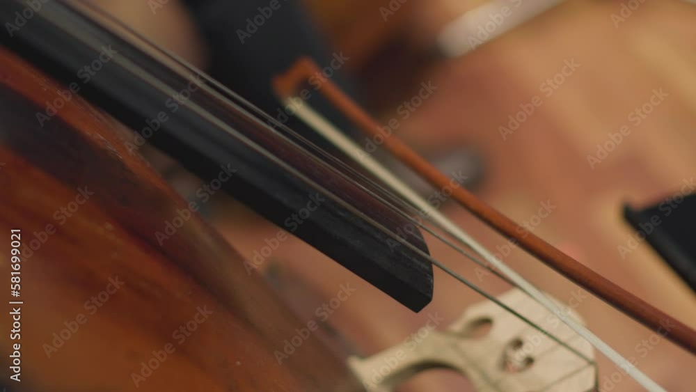 A slow motion video of a musician playing an acoustic double bass with a bow during a classical symphony orchestra rehearsal A slow motion video of a musician playing an acoustic double bass with a bow during a classical symphony orchestra rehearsal