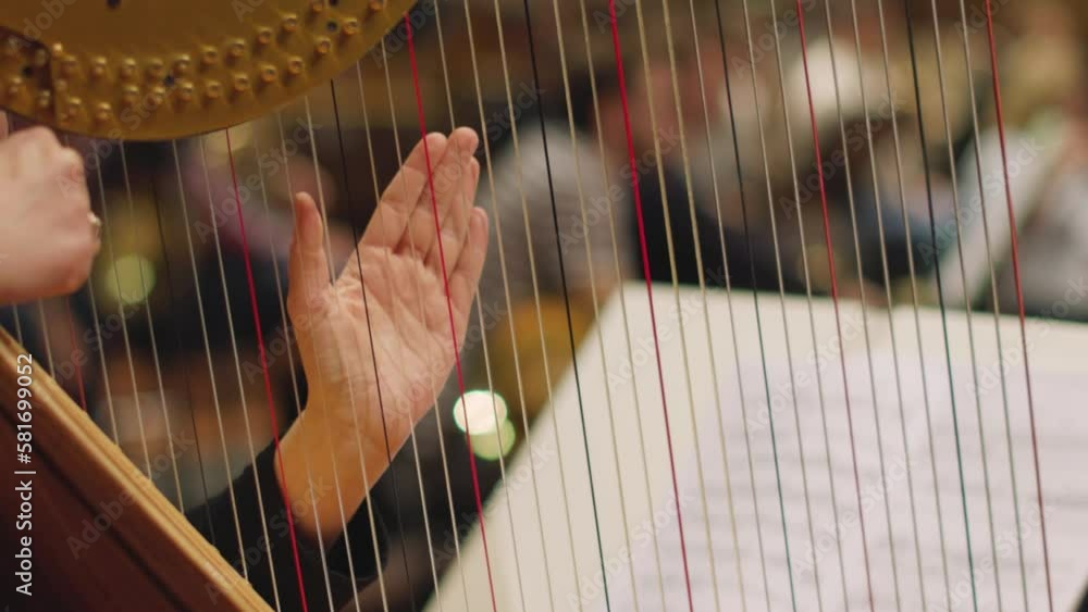 A slow motion video of a musician playing the harp by plucking only on one string during a