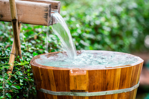 water flowing into a glass, Wooden barrels for natural onsen, steam hot water from natural hot springs, soft focus.