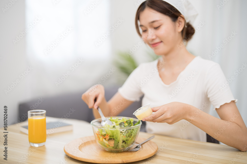 Happy beautiful Asian woman eating healthy food with vegan.salad in the kitchen at home. Happy beautiful Asian woman eating healthy food with vegan.salad in the kitchen at home.