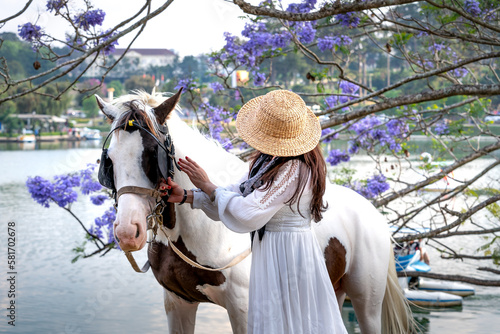 A female tourist and a white horse on the banks of Xuan Huong Lake in Da Lat Town, Lam Dong Province, Vietnam photo