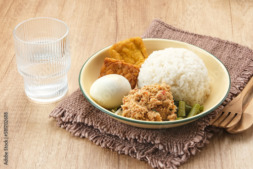 Nasi Gudangan, rice served with various vegetable with grated coconut seasoned and various side dishes. Indonesian food photo