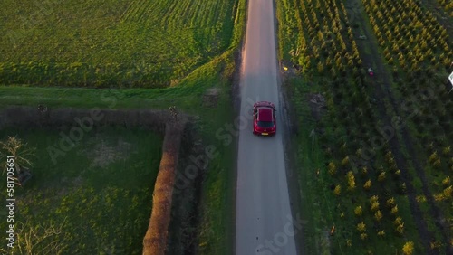 Aerial drone shot of Alfa Romeo car driving underneath and away from drone. photo