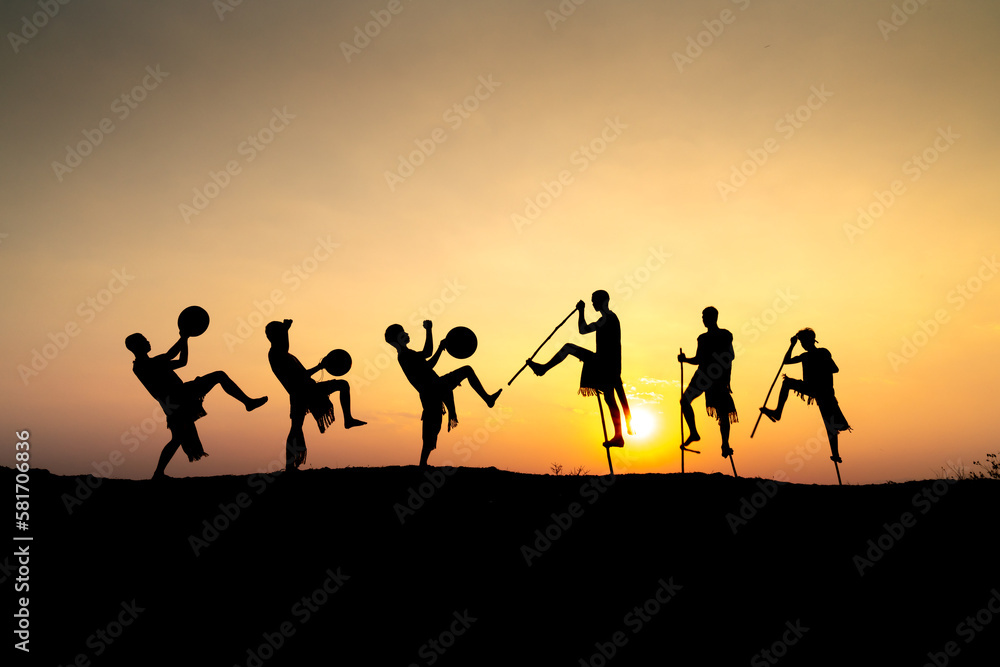 Silhouettes of Ede boys and girls performing their traditional dance during sunset in Pleiku town, Gia Lai province, Vietnam.