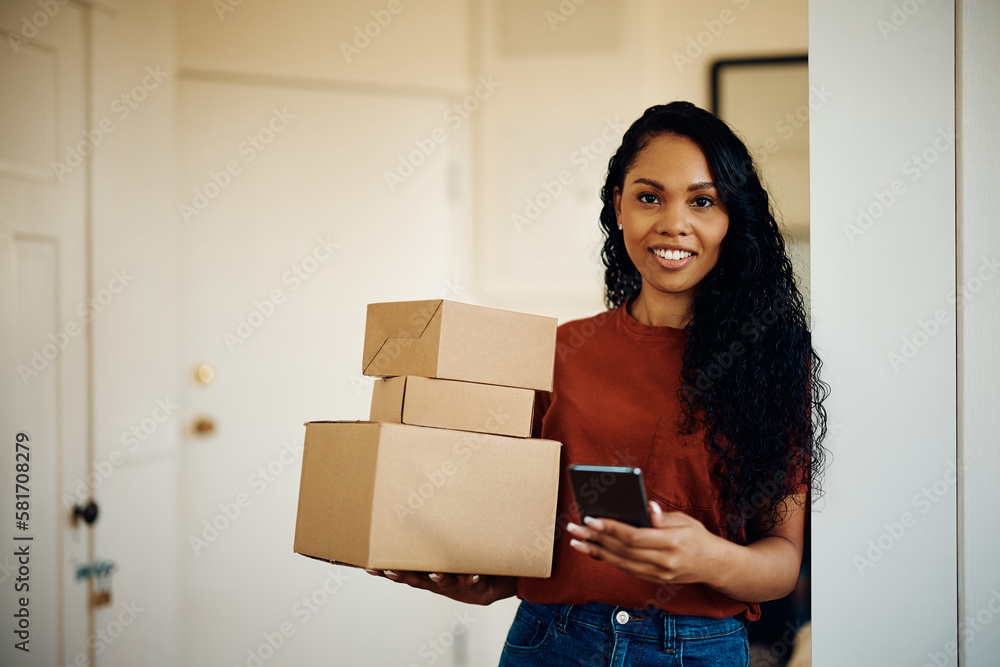 Happy black woman using mobile phone while receiving home delivery and looking at camera. Happy black woman using mobile phone while receiving home delivery and looking at camera.