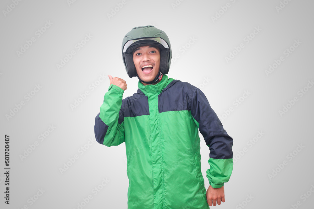Fototapeta premium Portrait of Asian online taxi driver wearing green jacket and helmet showing good job sign, thumb up. Isolated image on white background