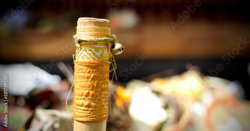 Tip of bamboo cane wrapped in gold and white color cloth, tied with small bell.