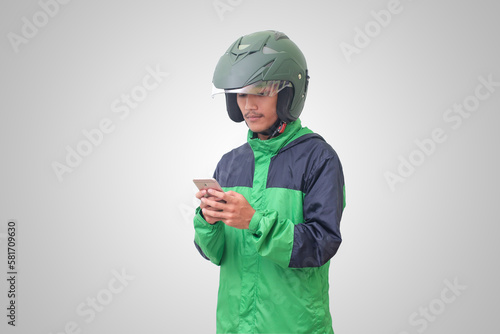 Portrait of Asian online taxi driver wearing green jacket and helmet holding mobile phone. Isolated image on white background