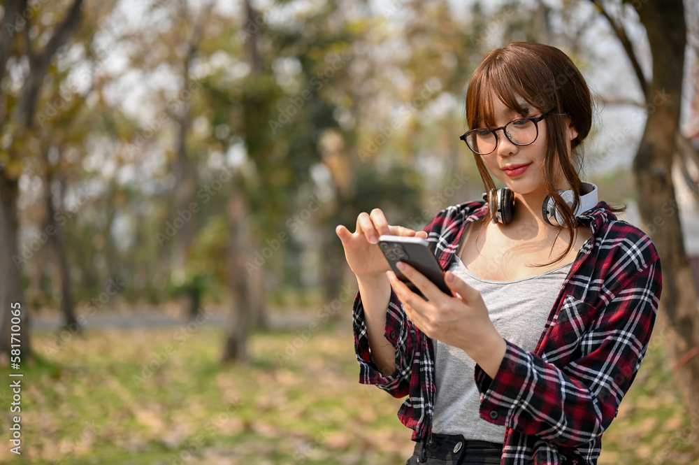 Beautiful Asian female college student using her phone while relaxing in the campus park. Beautiful Asian female college student using her phone while relaxing in the campus park.