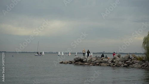 Nikopol, Ukraine -  October 3, 2021. Reggata. Yachting Competition. A group of People watch a standing Sailing Competition on the beach photo