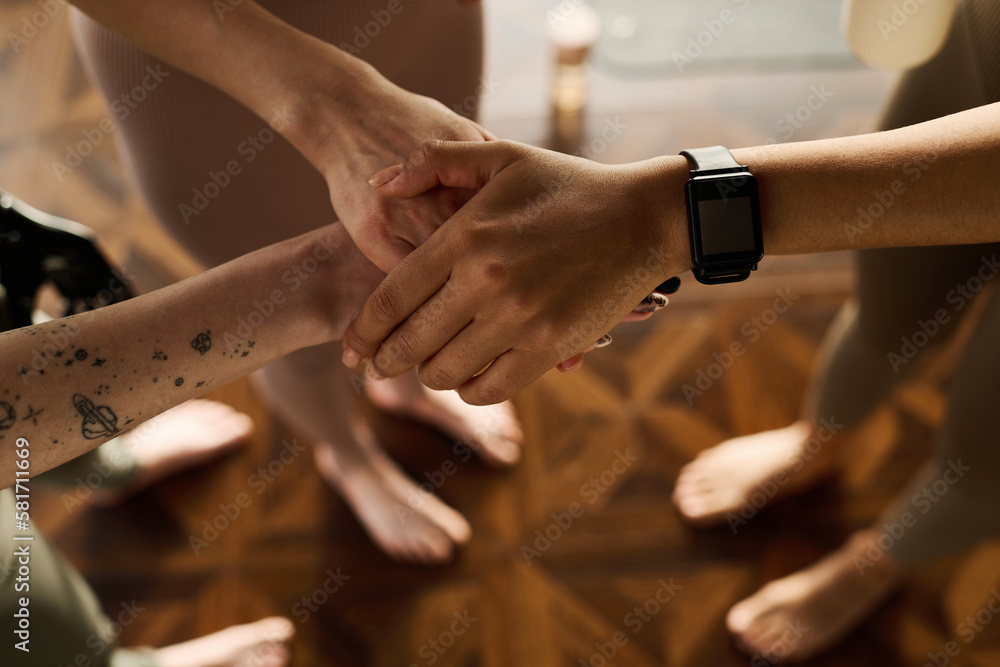 Close-up of friends holding hands while exercising in team during sport training Close-up of friends holding hands while exercising in team during sport training