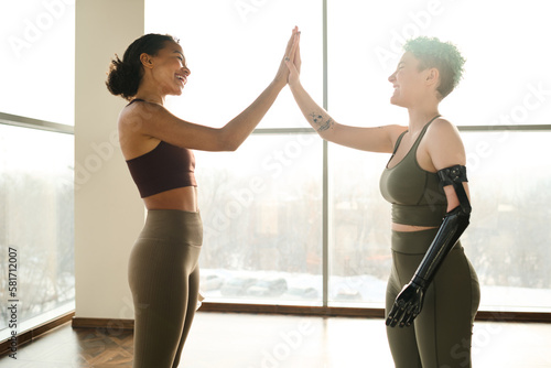Pretty girl with prosthetic arm giving high-five to instructor while they training in gym © AnnaStills