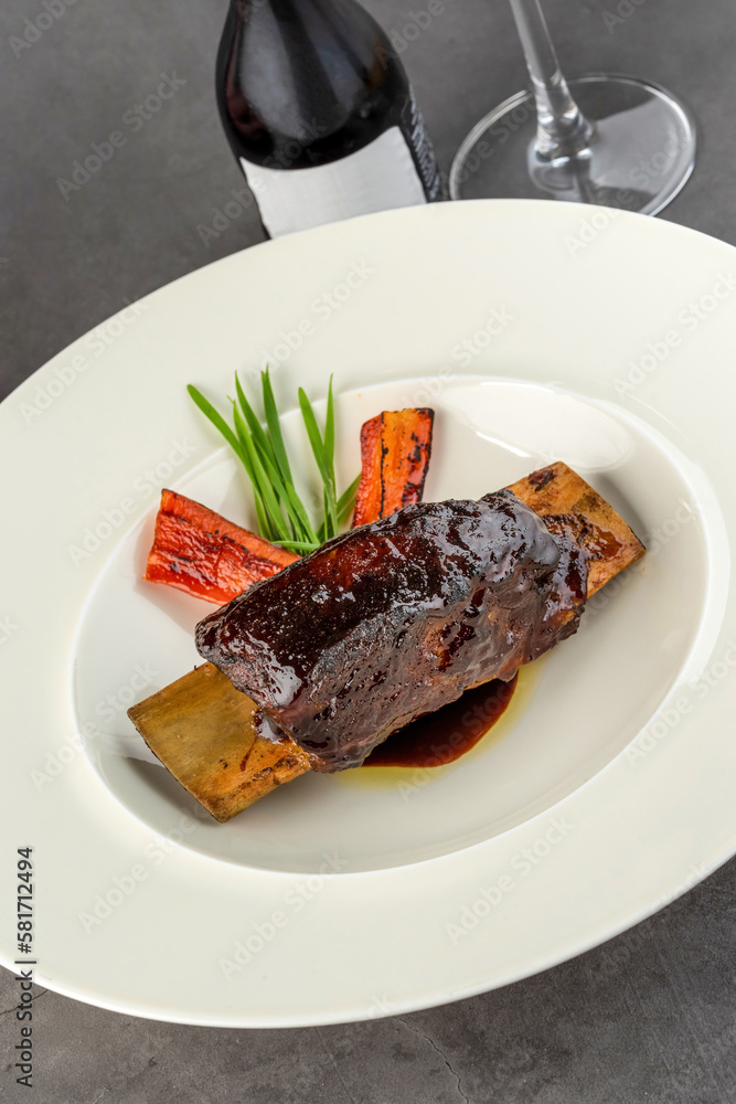Long cooked marinated beef ribs on a white porcelain plate