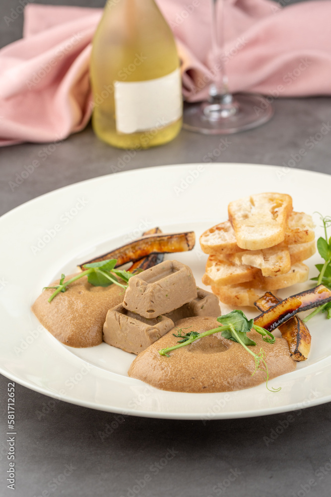 Foie gras with sauce and crispy bread on a white porcelain plate