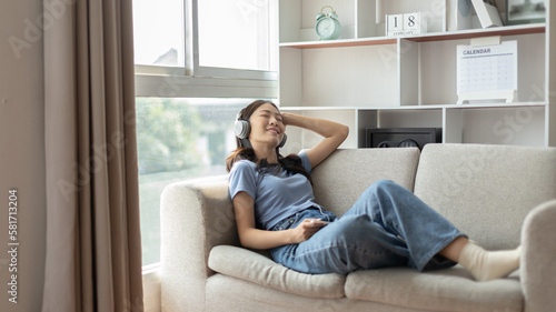 Woman happily listening to music on her favorite sofa in the living room, Relaxation time, Happy time, Feel good, Happy women resting at work after work is finished, Chill, Fatigue is eased.